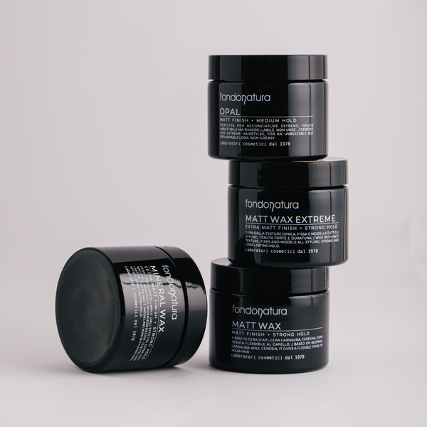 Keturios Fondonatura plaukų vaško pakuotės sudėtos viena ant kitos. Produkto etiketės aiškiai matomos, išskiriant skirtingus fiksacijos lygius.