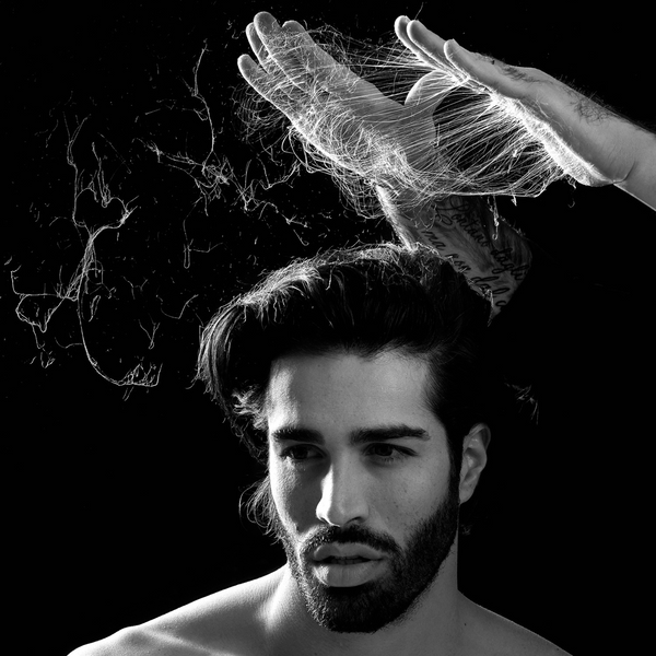 Juodai baltas vaizdas, kuriame stilistas rankomis formuoja vyro plaukus, naudojant Fondonatura Matt Wax. Matomos ištemptos plaukų formavimo tekstūros.