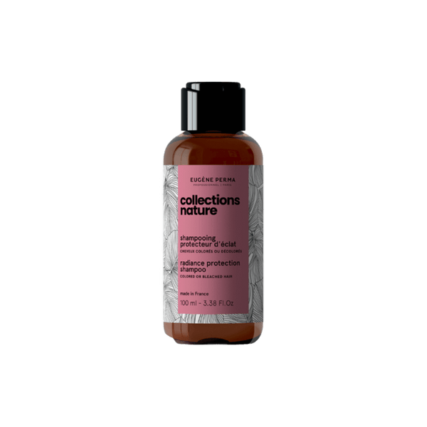 Nature Radiance Protection Shampoo – tamsaus gintaro spalvos buteliukas su juodu dangteliu ir rožine etikete. Etiketėje nurodytas produkto pavadinimas, paskirtis dažytiems ar šviesintiems plaukams ir talpa – 100ml